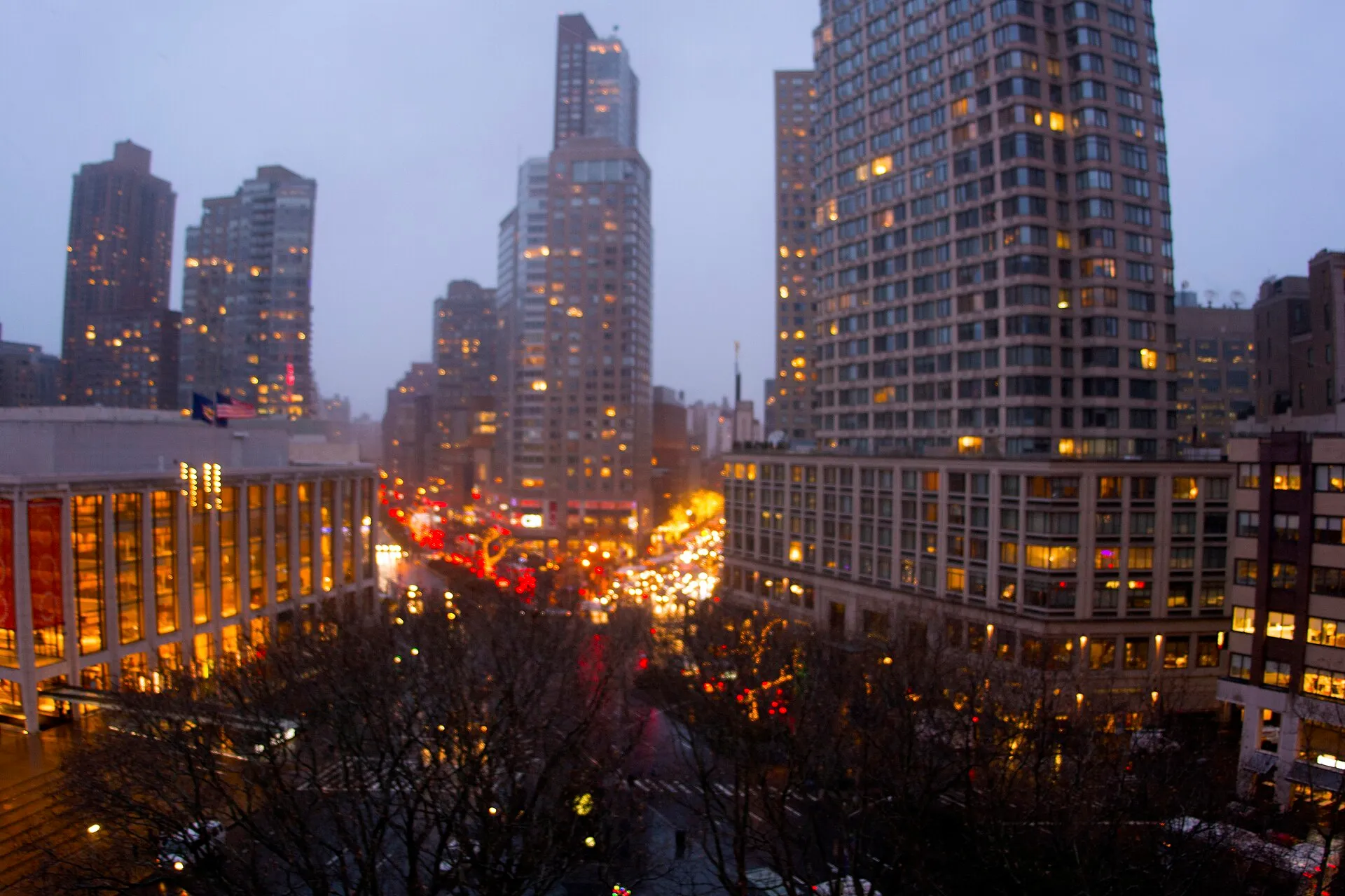 Manhattan at dusk, office and apartment windows lit above the evening traffic